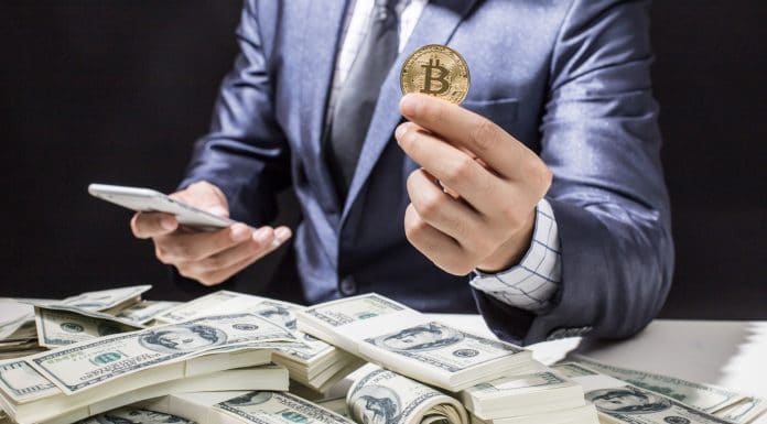Homem segurando bitcoin próximo de notas de Dólar