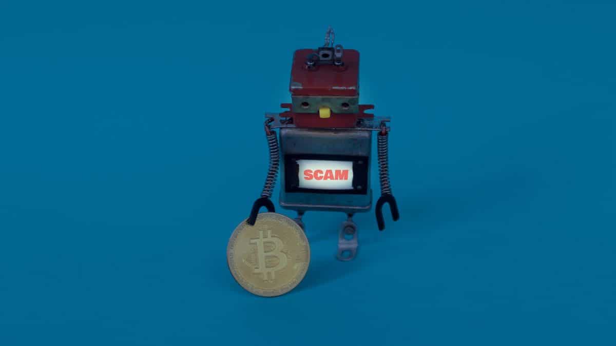 Robô próximo de bitcoin com placa de scam