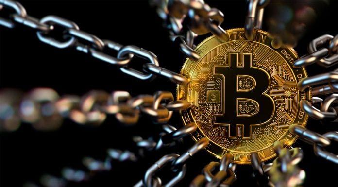 Criptomoeda Bitcoin presa a correntes, simbolizando regulamentação do setor.