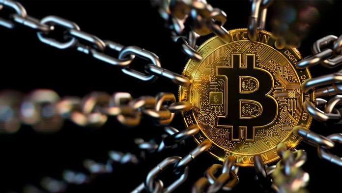 Criptomoeda Bitcoin presa a correntes, simbolizando regulamentação do setor.