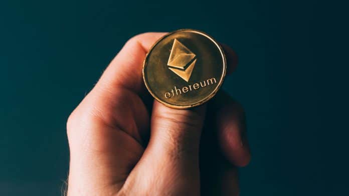 Mão segurando moeda de Ethereum.