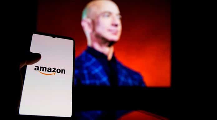 Celular com logo da Amazon na frente de foto de Jeff Bezos, fundador da empresa.