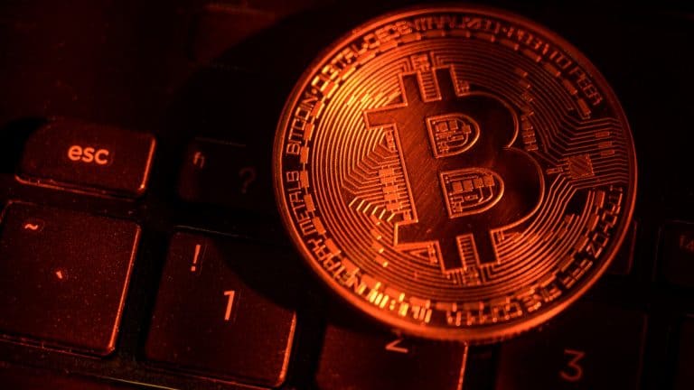 Bitcoin em luz vermelha em cima de um teclado de computador