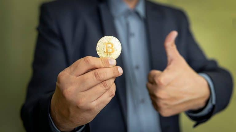 Bitcoin em uma mão com sinal de positivo na outra