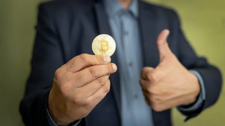 Bitcoin em uma mão com sinal de positivo na outra