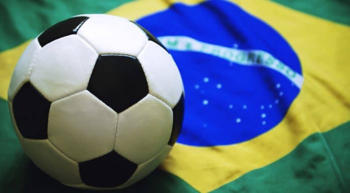 Bola de futebol próximo de bandeira do Brasil