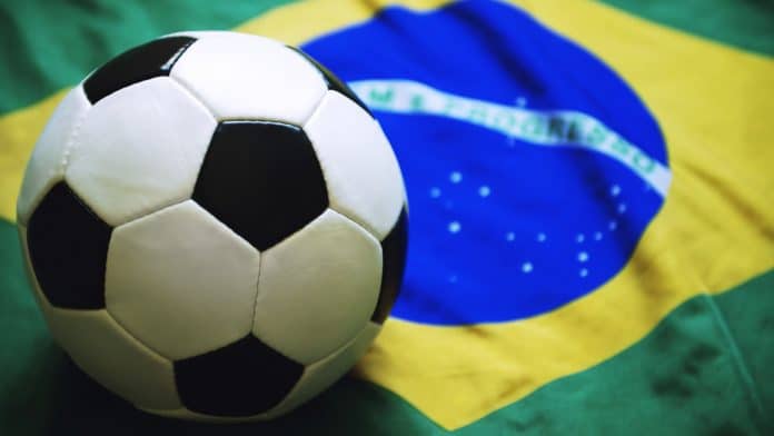 Bola de futebol próximo de bandeira do Brasil