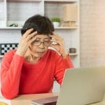 Depressão de mulher idosa e séria sobre verificar o gráfico de preços do Bitcoin na exchange no laptop