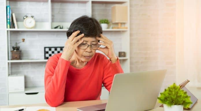 Depressão de mulher idosa e séria sobre verificar o gráfico de preços do Bitcoin na exchange no laptop