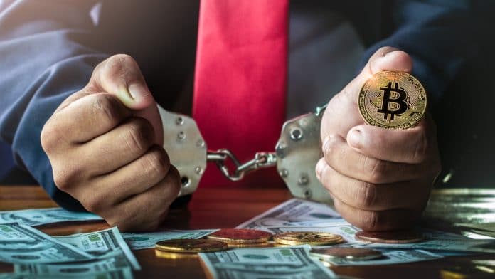 Homem preso e segurando bitcoin
