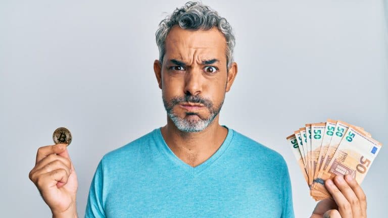 Homem segura notas e Bitcoin preocupado