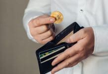 Mãos de um trabalhador colocando bitcoin em uma carteira vazia