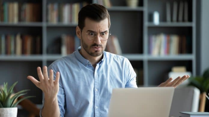 Trader de criptomoedas indignado ao olhar para computador bitcoin e saques