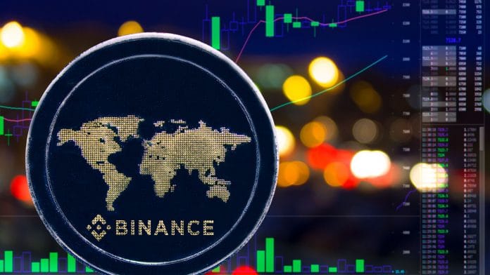 Logotipo da Binance em moeda, em frente à exchange.