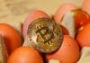Moeda de Bitcoin sobre dúzia de ovos.