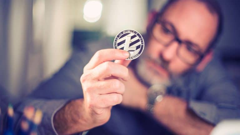 Investidor segurando moeda física de Litecoin (LTC).