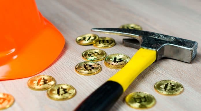 Picareta e moedas físicas de Bitcoin.