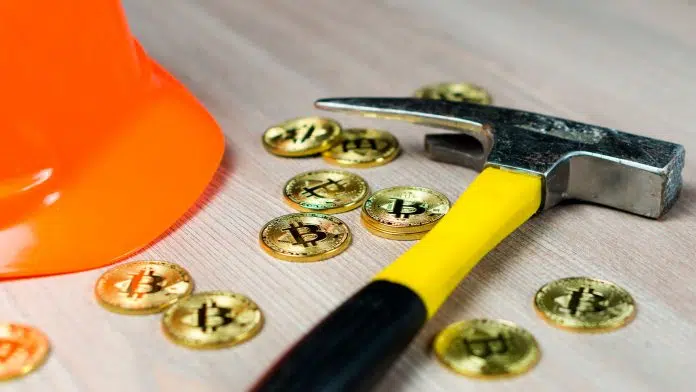 Picareta e moedas físicas de Bitcoin.