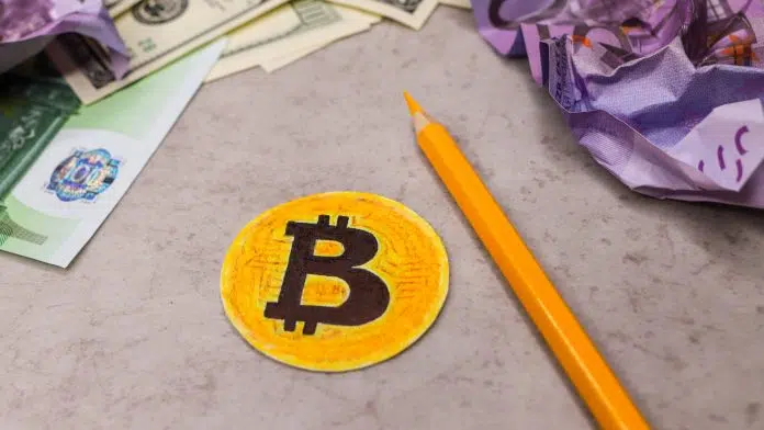 Bitcoin falso colorido, próximo de notas amassadas
