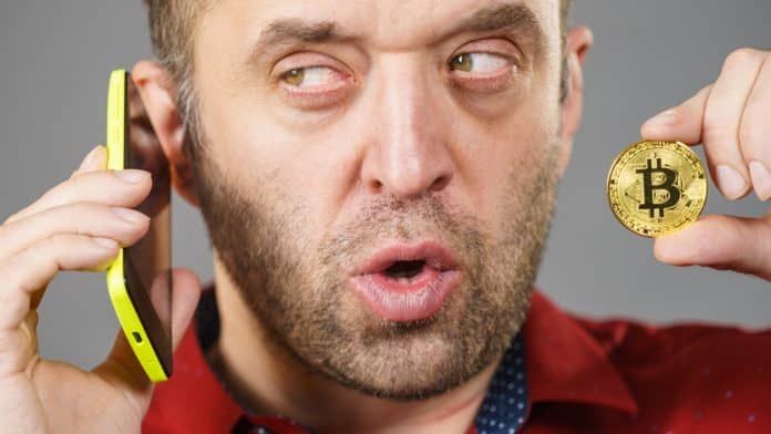 Homem com olhar suspeito em conversa pelo telefone e segurando Bitcoin