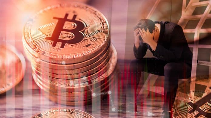 Homem desesperado ao lado de pilha de bitcoin