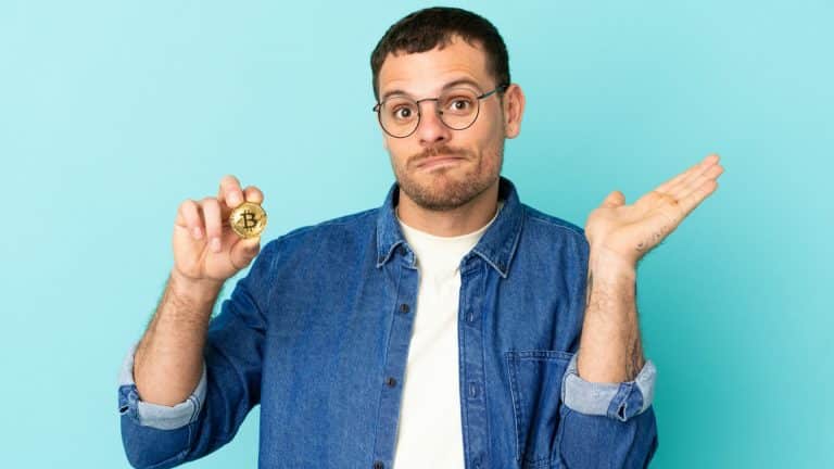 Homem segurando Bitcoin em dúvida sobre queda ou alta do bitcoin