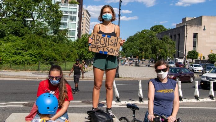 Jovem manifestante segurando placa para abolir prisões