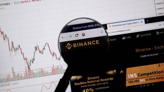 Lupa de olho no símbolo da corretora Binance, maior do mundo de volume em criptomoedas