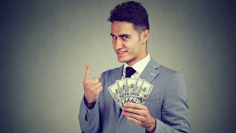 Trader com notas de dinheiro na mão e olhar ganancioso