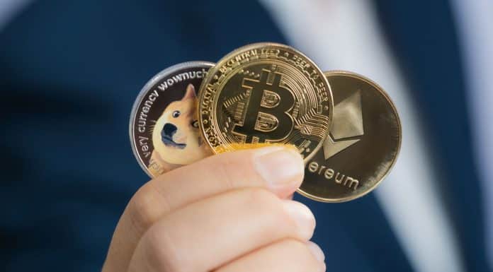 Investidor segurando moedas físicas de Dogecoin, Bitcoin e Ethereum.