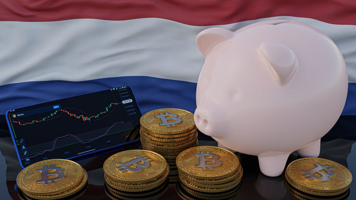 Moedas de bitcoin, celular com gráfico de preço e cofre de porquinho em frente à bandeira da Holanda.