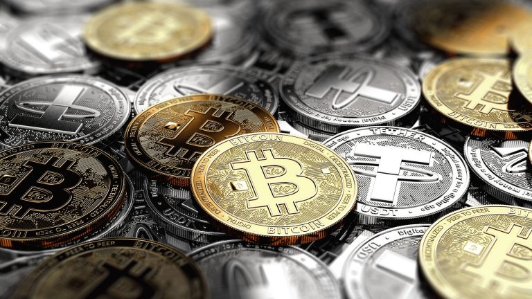 Moedas físicas de Bitcoin e da stablecoin Tether.