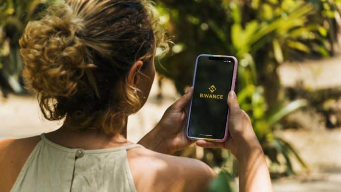 Brasileira usando aplicativo da Binance no celular.