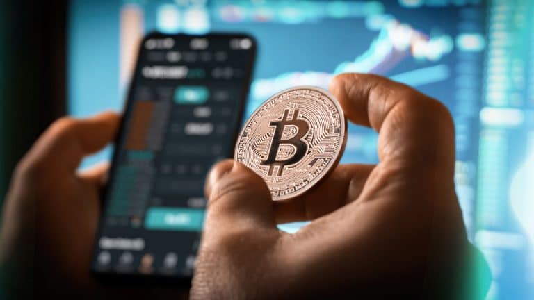 Investidor em exchange de criptomoedas segurando moeda de Bitcoin.