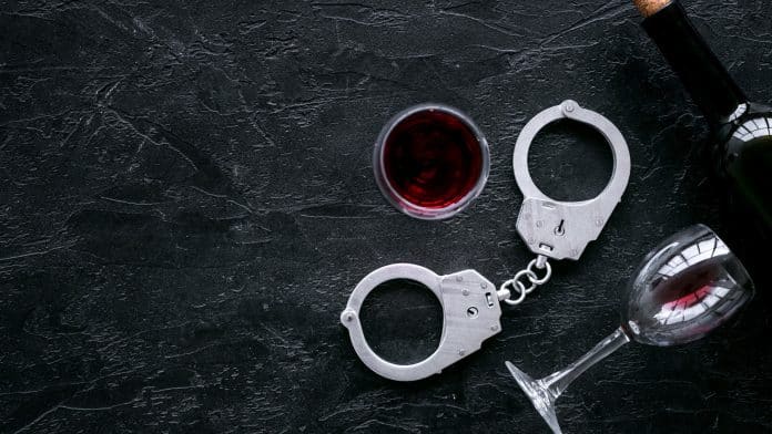 Algemas da polícia próximo de garrafa e taças de vinho