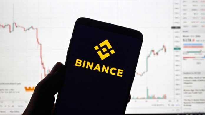 Aplicativo da Binance com gráfico de criptomoedas ao fundo