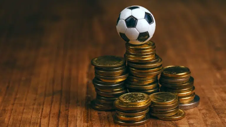 Bola de futebol sobre pilha de moedas