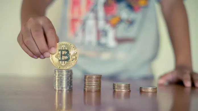 Criança empilhando moedas de bitcoin, criptomoedas e educação financeira para crianças e adolescentes