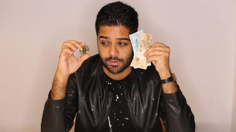 Homem olhando para Bitcoin enquanto segura notas de Real