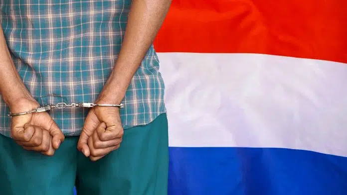 Homem preso com bandeira da Holanda ao lado