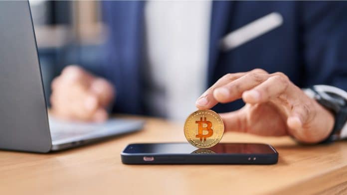 Jovem colocando bitcoin em celular
