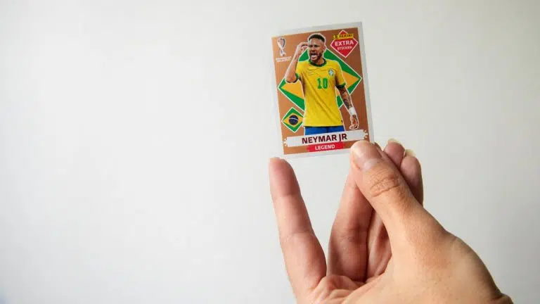 Mão segurando figurinha do Neymar Jr para o álbum da Copa do Mundo 2022, produzida pela Panini