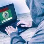 Visão traseira de um hacker vestindo um capuz e roubando bitcoins em uma tela de laptop e criptomoedas