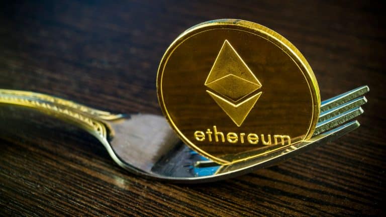 Garfo segurando moeda de Ethereum, simbolizando bifurcação da criptomoeda.