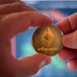 Pessoa segurando moeda física de Ethereum.