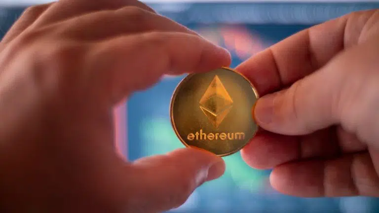 Pessoa segurando moeda física de Ethereum.
