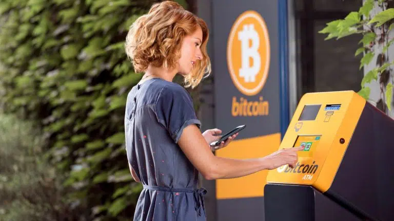 Mulher utilizando caixa eletrônico de Bitcoin.
