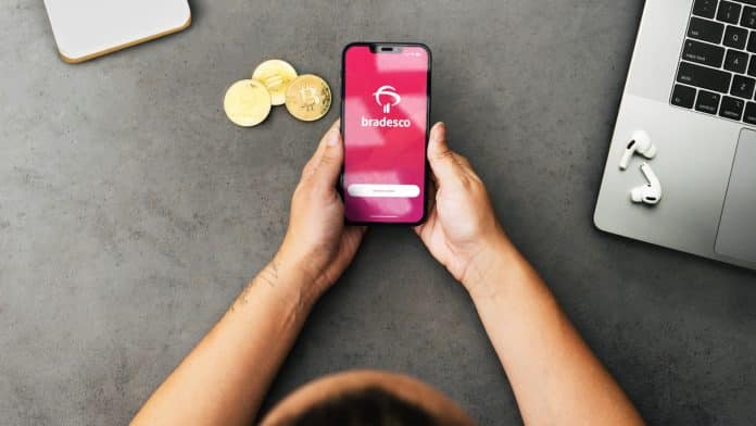 Aplicativo do Bradesco próximo de criptomoedas na mão de mulher