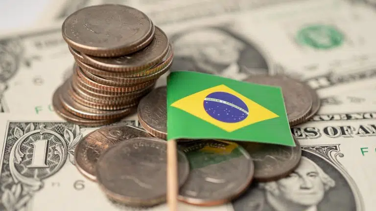 Bandeira do Brasil sobre dólares em moeda e nota