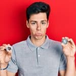 Homem depressivo segurando bitcoin e ethereum, criptomoedas famosas